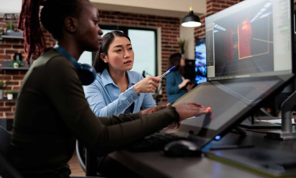 Production department 3D artist team leader with multiple displays on desk working on digital